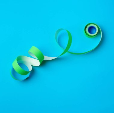 Mavi arka planda yeşil yapışkan etiketli bükülmemiş makara.