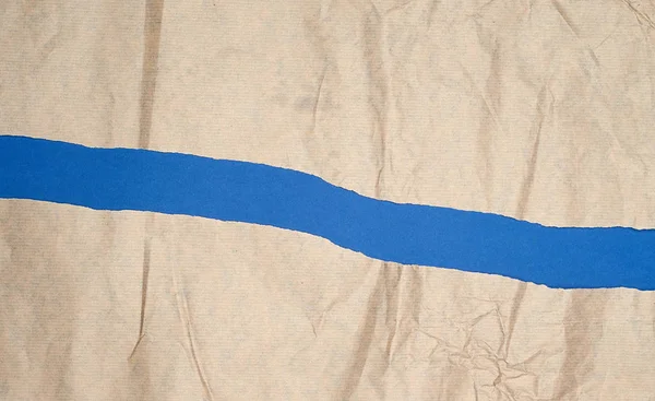 Gescheurd bruin vel papier op een blauwe achtergrond, volledig frame — Stockfoto