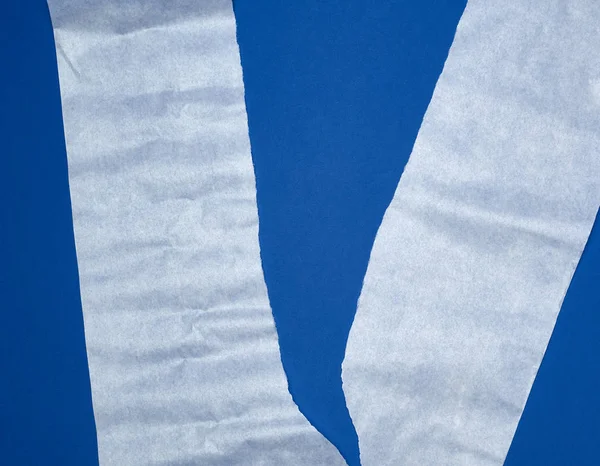 Gescheurd stuk wit perkamentpapier op een blauwe achtergrond — Stockfoto