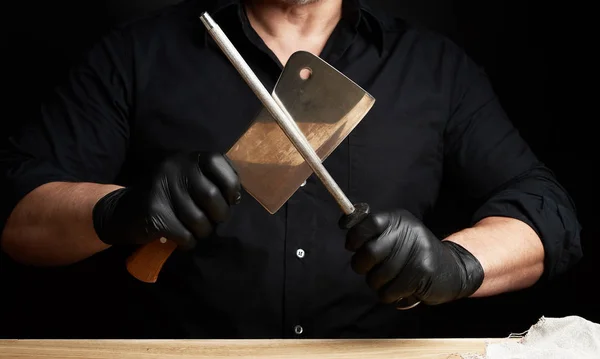 Chef em uma camisa preta e luvas de látex preto afiar uma cozinha k — Fotografia de Stock