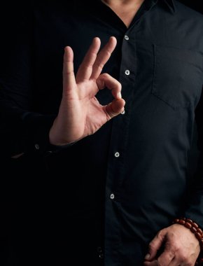 Siyah tişörtlü adam eliyle Gürcü Mudra 'sını gösteriyor.