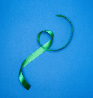 yeşil ipek ince kurdele mavi arka planda bükülmüş