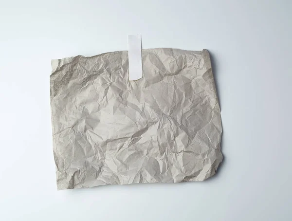 Γκρι τσαλακωμένο φύλλο χαρτιού κολλημένο με λευκή κολλητική ταινία — Φωτογραφία Αρχείου