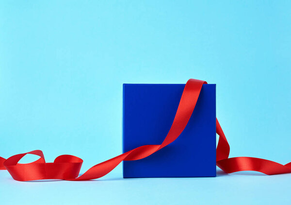 square blue cardboard box for a gift and twisted silk red ribbon