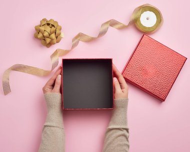 two female hands holding a square empty gift box