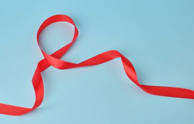 kırmızı ipek ince kurdele mavi arka planda bükülmüş