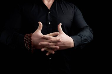 Siyah gömlekli adam parmaklarını çapraz yapıp Vajrap yapıyor.
