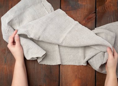 İki kadın eli gri bir mutfak havlusunu tutuyor. 