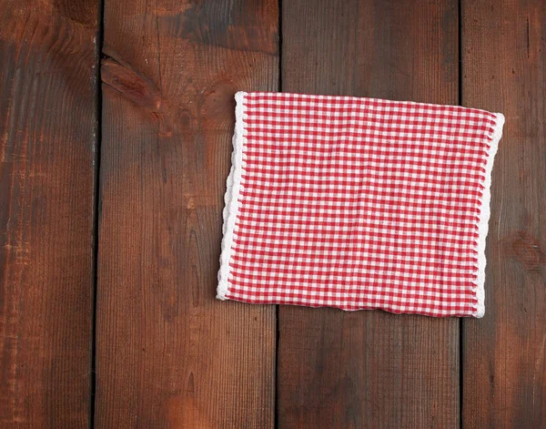 Witte rode geruite keukendoek op een bruine houten achtergrond — Stockfoto