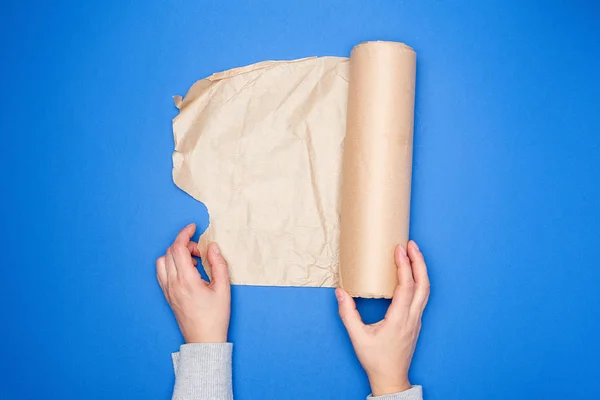 Két kéz kezében egy tekercs barna pergamenpapír egy kék háton — Stock Fotó
