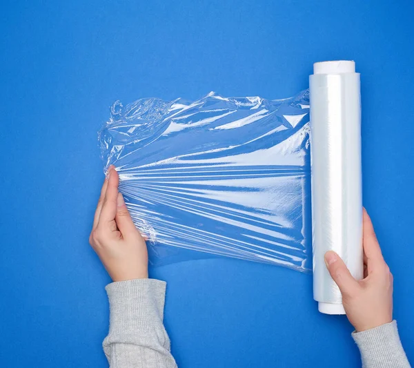 Hand hält eine große Rolle gewickelter weißer transparenter Folie für die Verpackung — Stockfoto