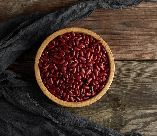 raw round red beans in a plate on a wooden table