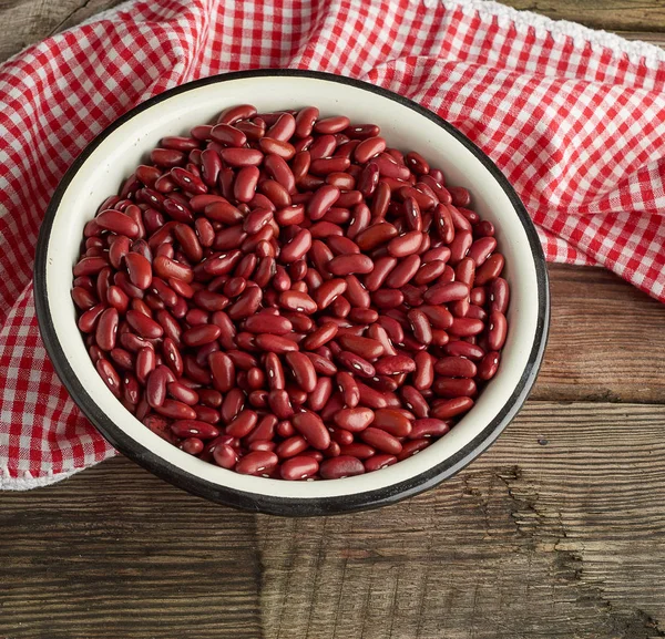 Сырая красная фасоль в тарелке на деревянном столе — стоковое фото