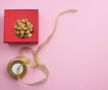 Kare kırmızı kutu altın kurdeleyle bağlanmış, tebrik konsepti.