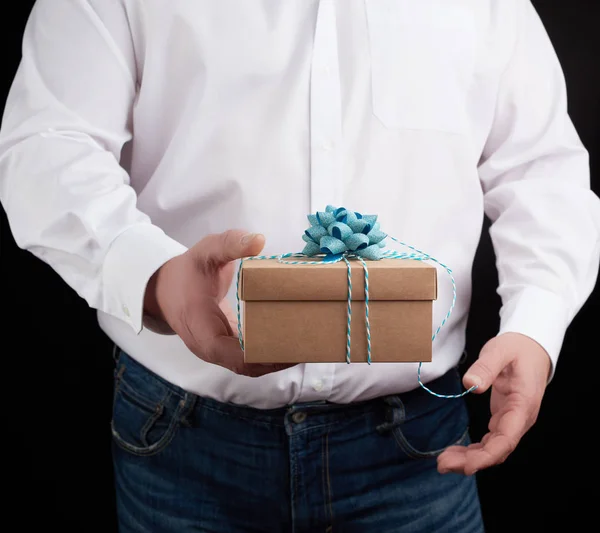 Человек в белой рубашке держит в руке закрытую коричневую коробку подарка о — стоковое фото