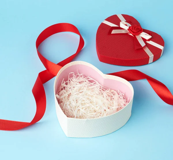 opened red heart-shaped gift box with a bow on a blue background