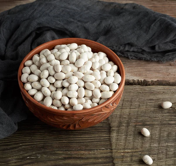 raw round white beans in a plate on a wooden table