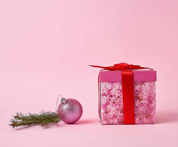 Růžová dárková krabička s lukem, zeleným smrkem a dekorativní růžovou — Stock fotografie