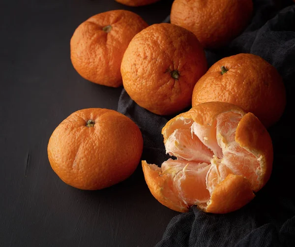 Skalad mogen apelsinmandarin och ett gäng oskalade runda hela — Stockfoto
