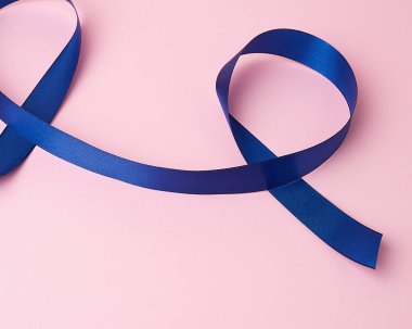 Koyu mavi ipek kurdele pembe arkaplanda döngü şeklinde bükülmüş.