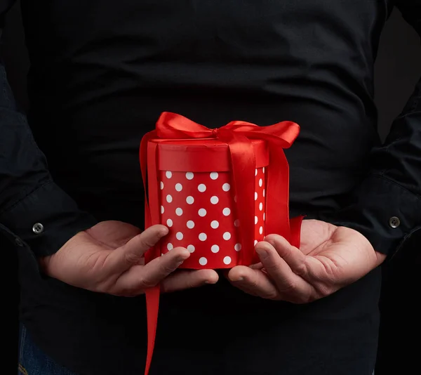 Main masculine tient une boîte en papier rouge avec un cadeau derrière son dos — Photo