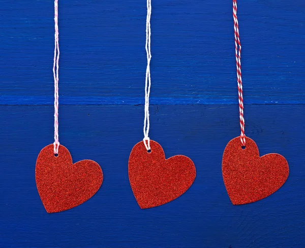 Papír červená lesklé dekorativní srdce visí na provaze na tmavé bl — Stock fotografie