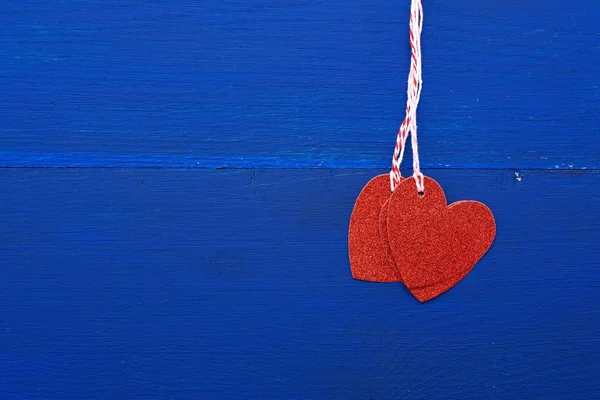Papír červená lesklé dekorativní srdce visí na provaze na tmavé bl — Stock fotografie