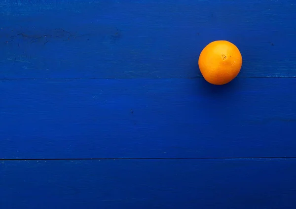 Orange entière ronde orange sur fond bleu foncé des planches — Photo