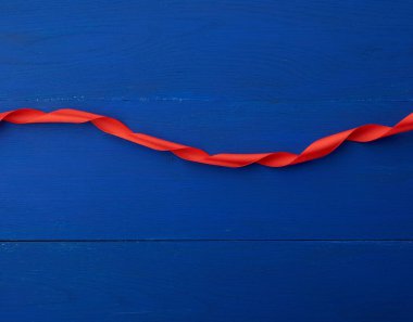 kırmızı ipek ince kurdele mavi ahşap arka planda bükülmüş