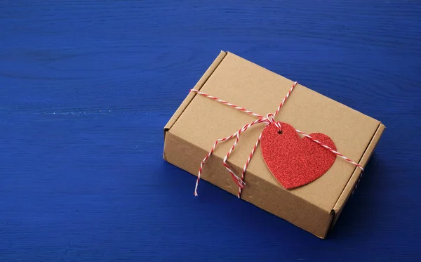 Rectangular brown box with a gift and a red paper heart tied to — 스톡 사진