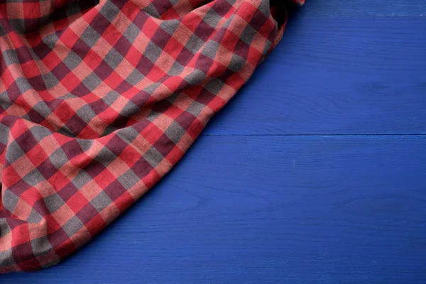 Tela a cuadros rojo sobre un fondo de madera azul — Foto de Stock