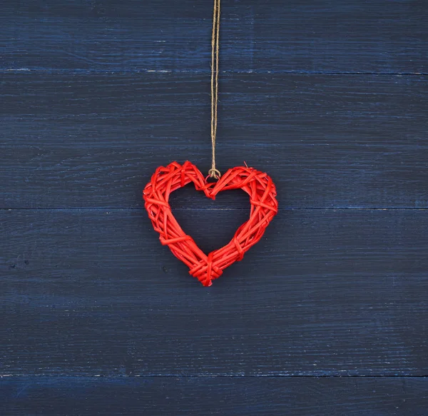 Červené proutěné dekorativní srdce visí na hnědém laně — Stock fotografie