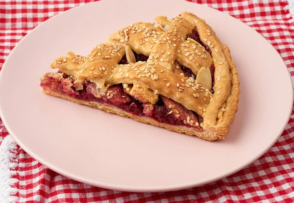 Triangular slice of baked cherry pie on a pink round plate — 스톡 사진