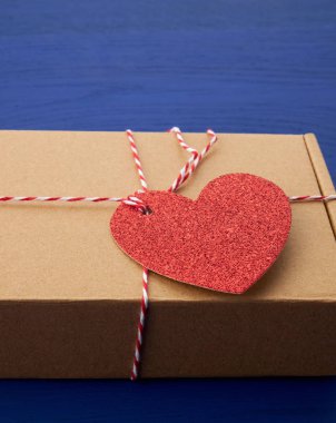 Bir hediye ile dikdörtgen kahverengi kutu ve bağlı kırmızı kağıt kalp 