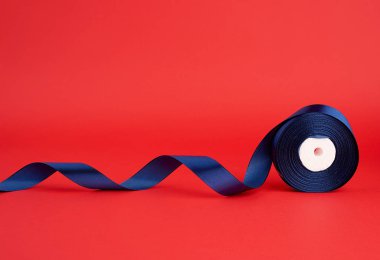 Kırmızı arka planda koyu mavi ipek parlak kurdele makarası