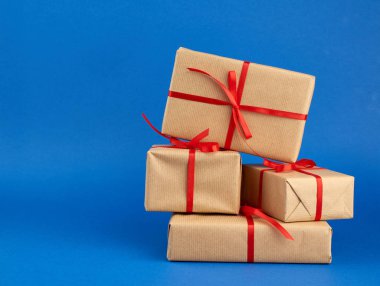 Kahverengi kağıda sarılı ve kırmızı bir fiyonkla bağlanmış kutular.