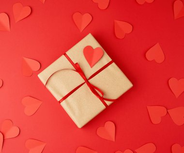 Kare kutu kahverengi kraft kağıdına sarılmış ve kırmızı ince bir şeyle bağlanmış.