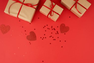 Kahverengi kraft kağıdına sarılı çeşitli kutular ve kırmızı bukle bağlanmış.