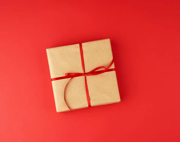 square box wrapped in brown kraft paper and tied with a red thin