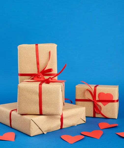 Stack of wrapped gifts in brown kraft paper and tied with a red — 스톡 사진