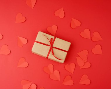 Kahverengi kraft kağıdına sarılı bir kutu ve kırmızı ince ipek bir R ile bağlanmış.