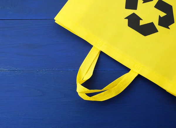 Bolso de viscosa amarillo reutilizable sobre fondo de madera azul — Foto de Stock