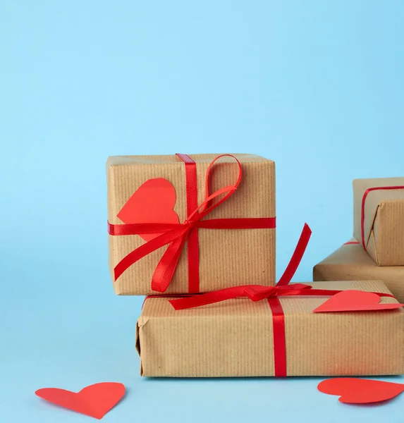 Stack of wrapped gifts in brown kraft paper and tied with a red — 스톡 사진