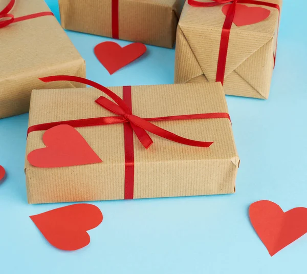 Wrapped gifts in brown kraft paper and tied with a red ribbon on — 스톡 사진