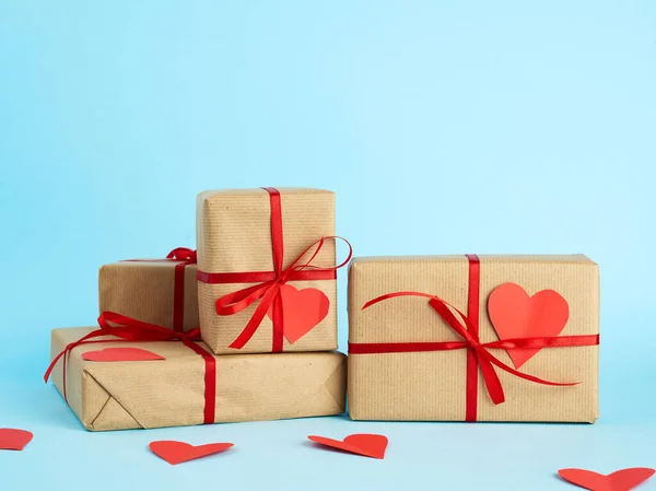 Stack of wrapped gifts in brown kraft paper and tied with a red — 스톡 사진