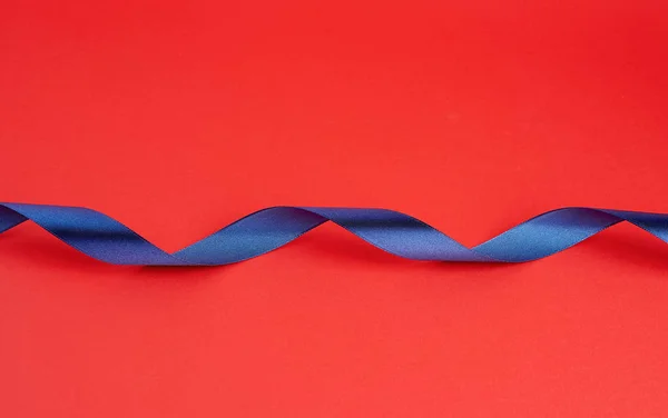 Крученый темно-синий шелк блестящая лента на красном фоне — стоковое фото