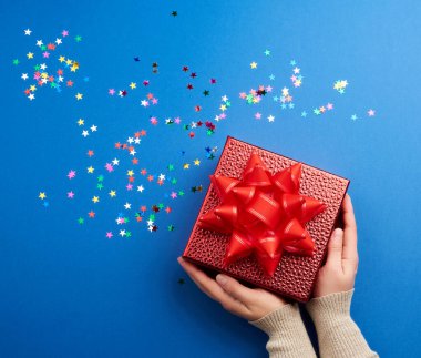 Kadın eli, büyük kırmızı bir fiyonklu, parlak kırmızı bir kutu tutar. 