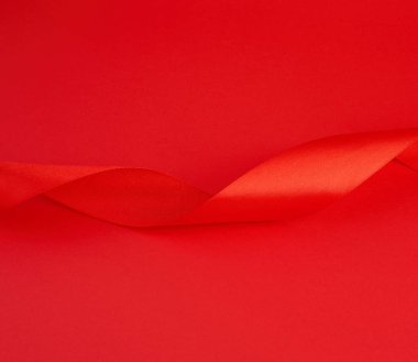 Kırmızı arka planda kırmızı ipek parlak kurdele, şenlik arzusu.