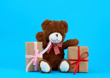 Kahverengi sevimli oyuncak ayı ve kahverengi eko kraft kağıdına sarılı hediyeler.