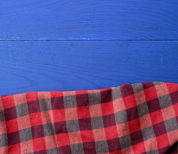 Tela a cuadros rojo sobre un fondo de madera azul — Foto de Stock